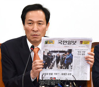 [포토] 신문들어 보이는 더불어민주당 우상호 원내대표