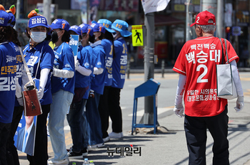 [포토] 민주당 선거유세장 지나는 국민의힘 선거사무원